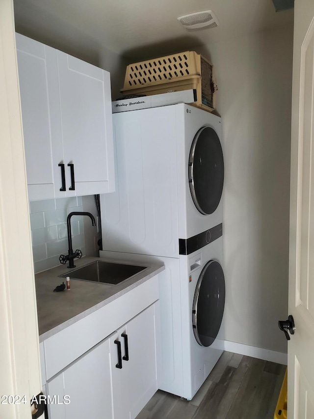 laundry room with cabinets, dark hardwood / wood-style floors, sink, and stacked washer and dryer