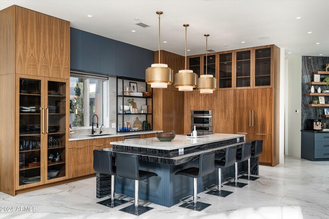 kitchen featuring decorative light fixtures, wood walls, sink, a kitchen breakfast bar, and a large island