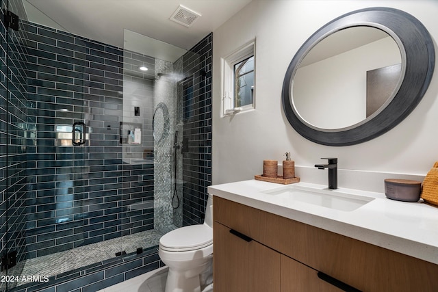 bathroom featuring vanity, tile patterned flooring, toilet, and a tile shower