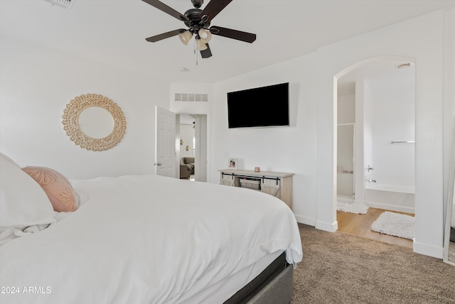 bedroom with ceiling fan, light carpet, and ensuite bath