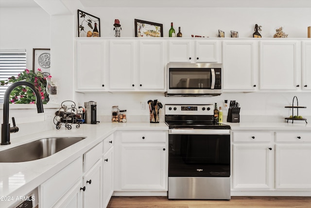 kitchen with white cabinets, light hardwood / wood-style floors, sink, and appliances with stainless steel finishes