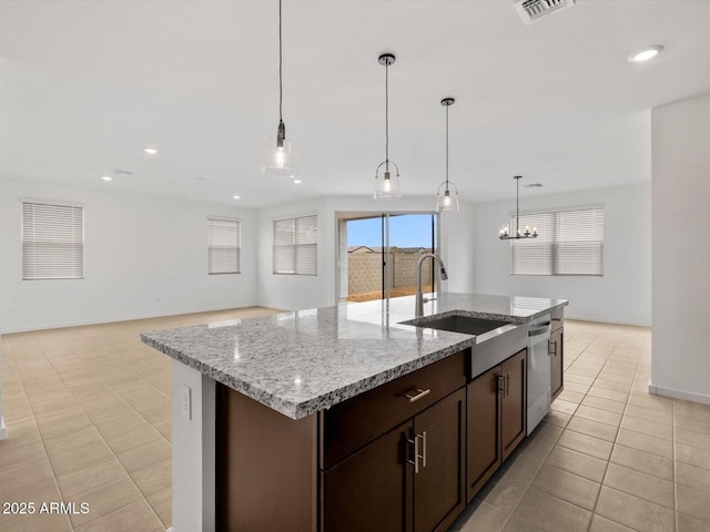 kitchen featuring dishwasher, a sink, hanging light fixtures, dark brown cabinetry, and light stone countertops