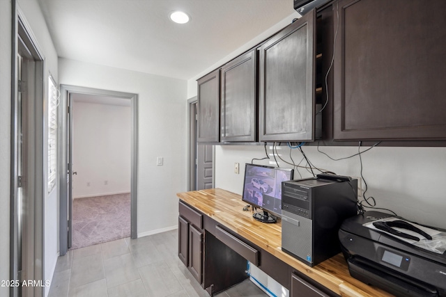 kitchen featuring light carpet, butcher block counters, and dark brown cabinetry