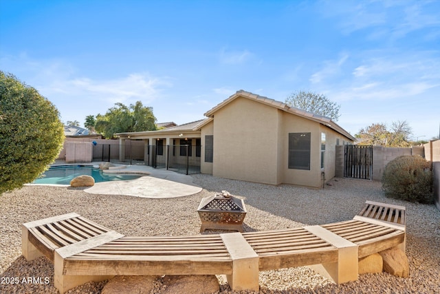 back of house featuring a fenced in pool, a patio area, and a fire pit