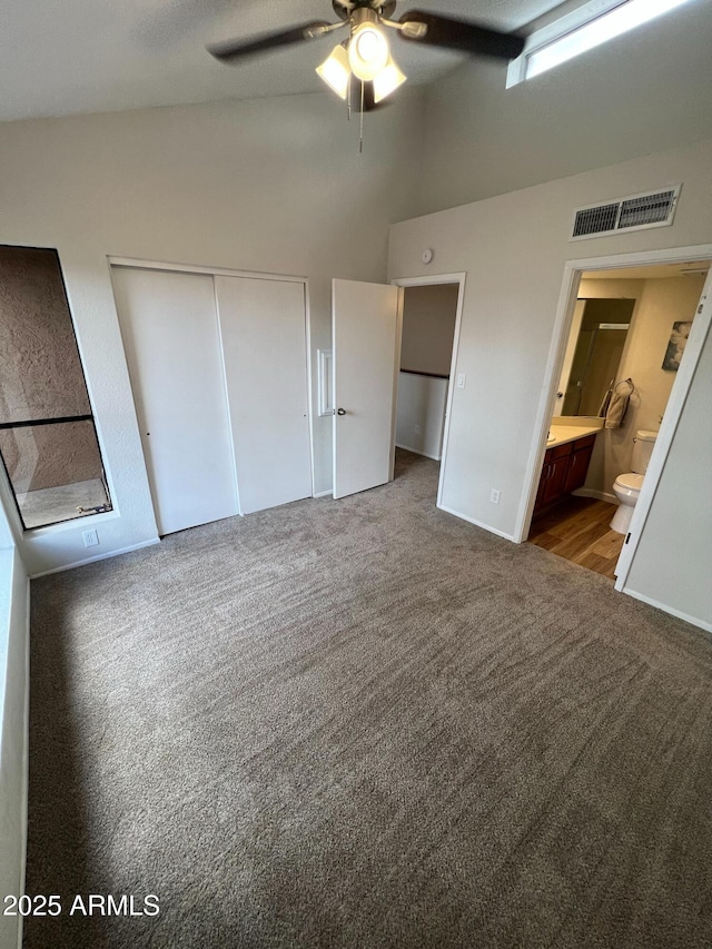 unfurnished bedroom featuring dark colored carpet, connected bathroom, high vaulted ceiling, and a closet