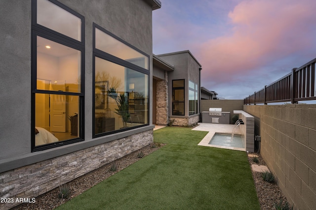 yard at dusk featuring an outdoor kitchen, a patio, and a fenced backyard