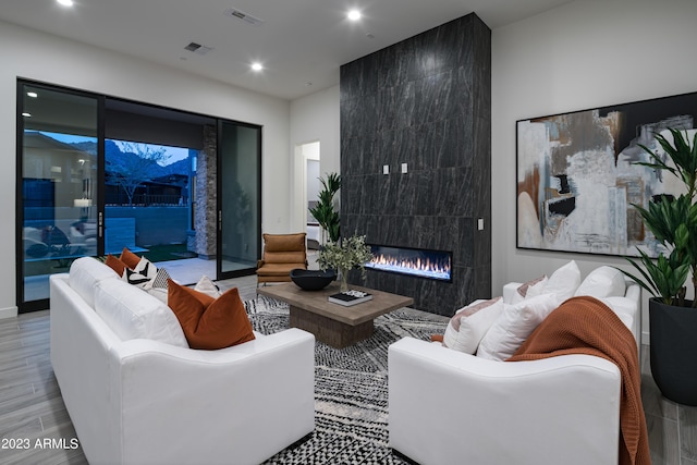 living room with a tiled fireplace, recessed lighting, wood finished floors, and visible vents