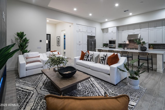 living area with visible vents, recessed lighting, light wood-type flooring, and baseboards