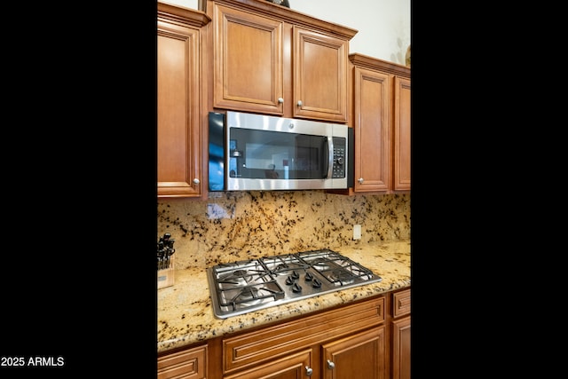 4229 E Nightingale Ln, Gilbert, AZ 85298 - kitchen featuring appliances with stainless steel finishes, backsplash, light stone counters, and brown cabinets