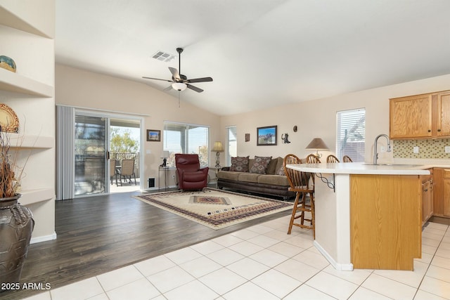 living room featuring lofted ceiling, sink, light tile patterned floors, and a healthy amount of sunlight