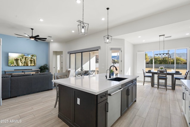 kitchen featuring stainless steel dishwasher, sink, decorative light fixtures, a healthy amount of sunlight, and a center island with sink