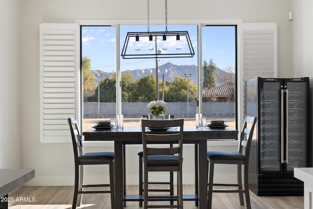 dining space featuring a mountain view, light hardwood / wood-style flooring, and wine cooler