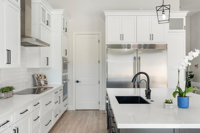 kitchen with white cabinets, pendant lighting, wall chimney range hood, and stainless steel built in refrigerator