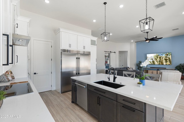 kitchen featuring pendant lighting, sink, white cabinetry, a barn door, and stainless steel appliances