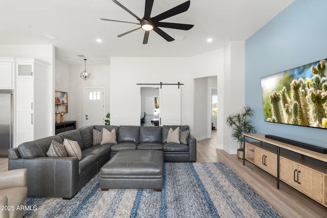 living room featuring hardwood / wood-style floors, ceiling fan, and a barn door