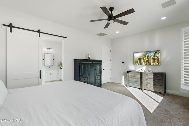 carpeted bedroom featuring ceiling fan, a barn door, and ensuite bath