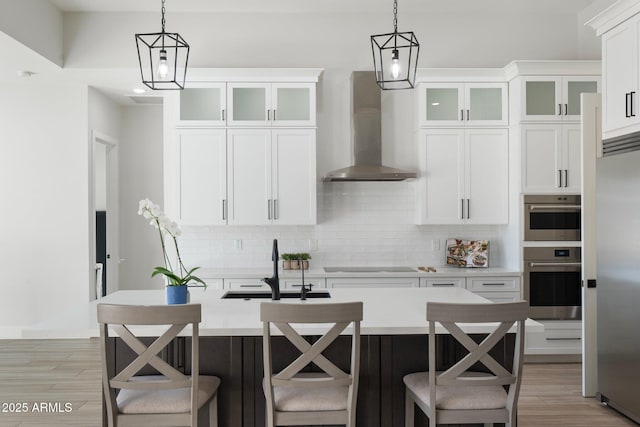 kitchen featuring hanging light fixtures, white cabinetry, decorative backsplash, and wall chimney range hood