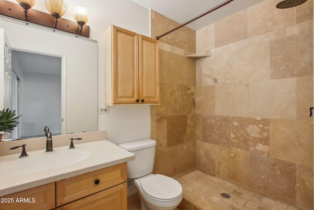 bathroom with a tile shower, vanity, and toilet