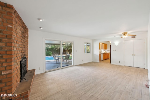 unfurnished living room with ceiling fan, light hardwood / wood-style floors, and a fireplace