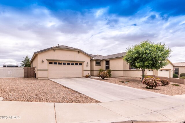 view of front facade with fence, driveway, a garage, stucco siding, and a tiled roof