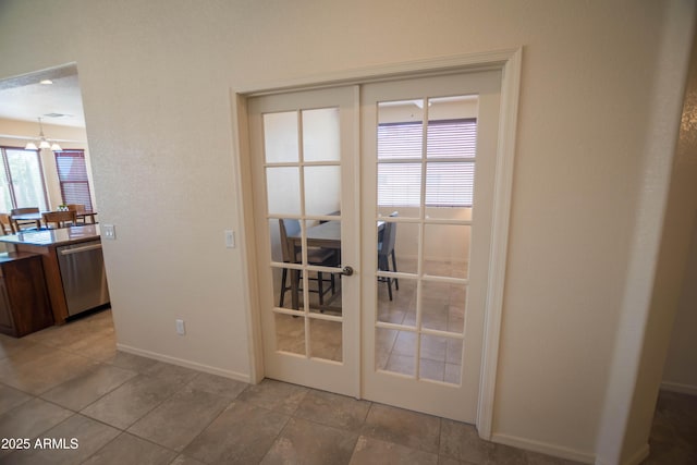 doorway featuring french doors, a chandelier, and baseboards