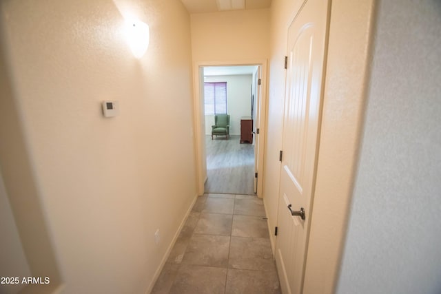 hallway featuring light tile patterned floors and baseboards