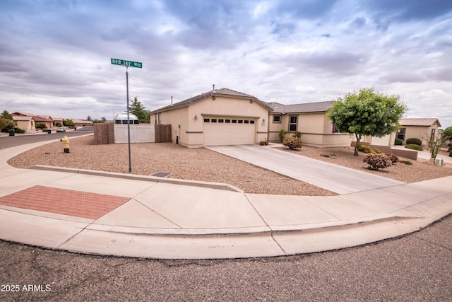 view of front of house with concrete driveway, stucco siding, a garage, and fence