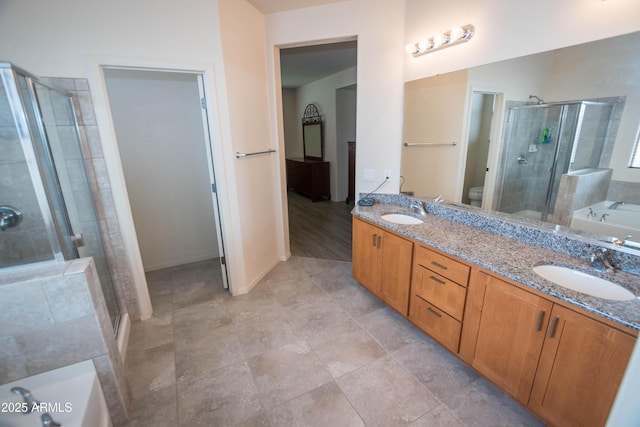 bathroom featuring a sink, toilet, a shower stall, double vanity, and a garden tub