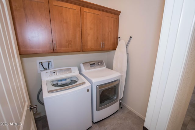 laundry room with baseboards, separate washer and dryer, and cabinet space