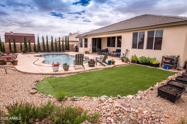 rear view of property with a fenced backyard, a patio, stucco siding, and a yard