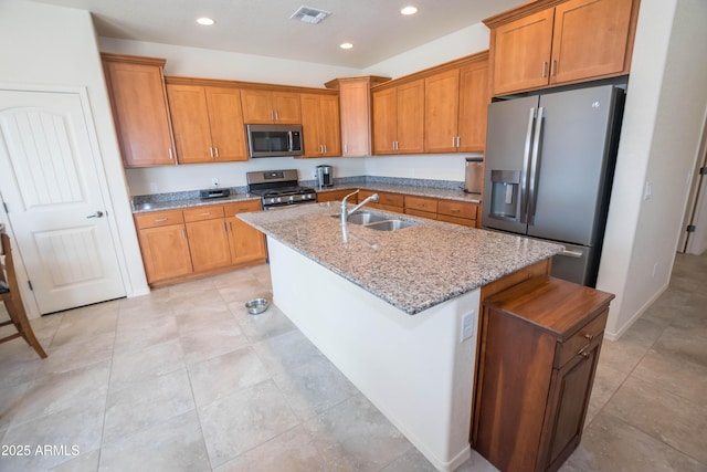 kitchen with a sink, brown cabinetry, stainless steel appliances, a kitchen island with sink, and visible vents