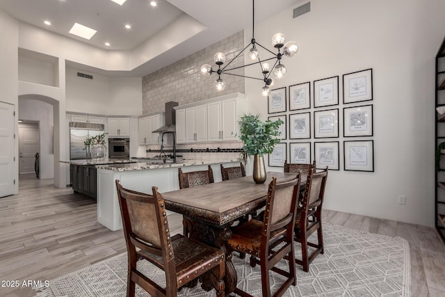 30600 N Pima Rd Unit 49, Scottsdale, AZ 85266 - dining room featuring light wood-style floors, visible vents, arched walkways, and a high ceiling