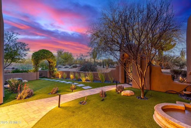 yard at dusk featuring a fenced backyard