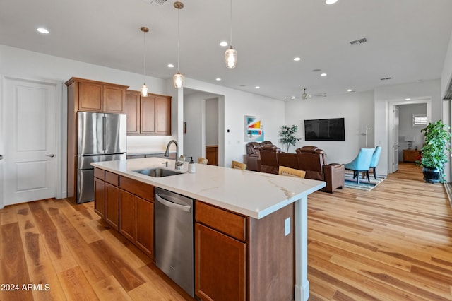 kitchen with a kitchen island with sink, hanging light fixtures, sink, ceiling fan, and stainless steel appliances