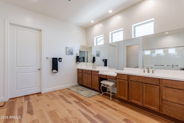 bathroom featuring vanity, wood-type flooring, a towering ceiling, and a shower with door