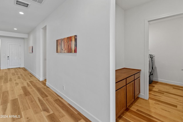 hall with washer and dryer and light hardwood / wood-style floors