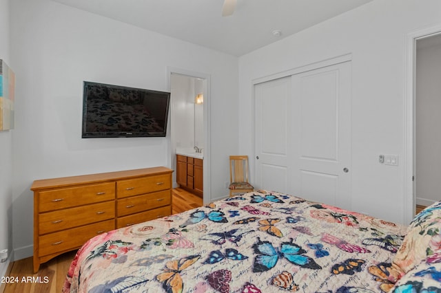 bedroom with ensuite bath, ceiling fan, sink, light hardwood / wood-style flooring, and a closet