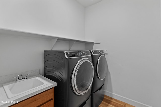 laundry area with independent washer and dryer, light hardwood / wood-style floors, and sink