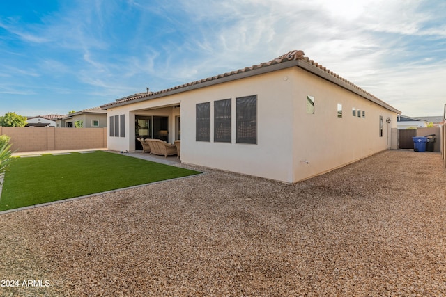 back of house featuring outdoor lounge area, a yard, and a patio area