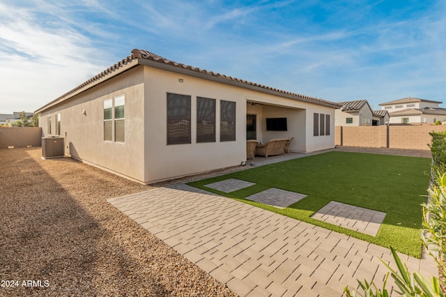 rear view of property with a yard, cooling unit, and a patio area