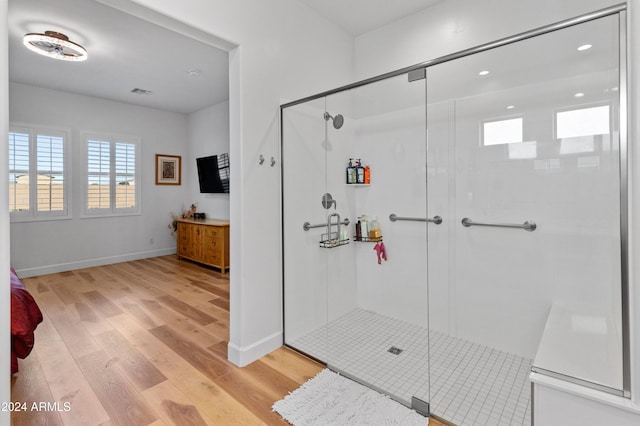 bathroom with a shower with shower door and hardwood / wood-style flooring