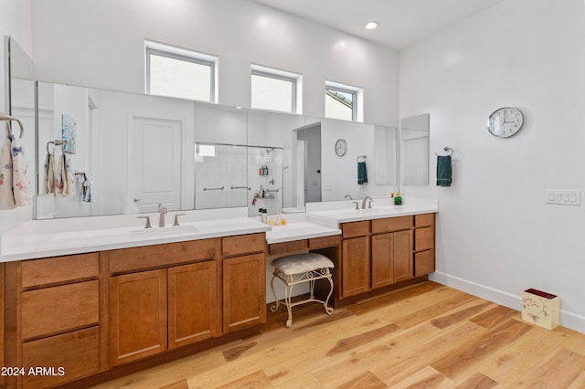 bathroom featuring vanity, wood-type flooring, a high ceiling, and walk in shower