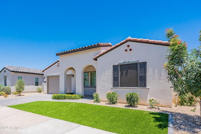 mediterranean / spanish-style house featuring a garage and a front lawn