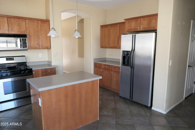 kitchen with a center island, appliances with stainless steel finishes, dark tile patterned flooring, and hanging light fixtures