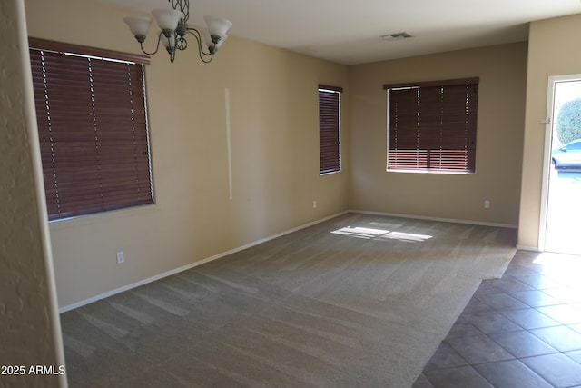 carpeted spare room featuring a notable chandelier