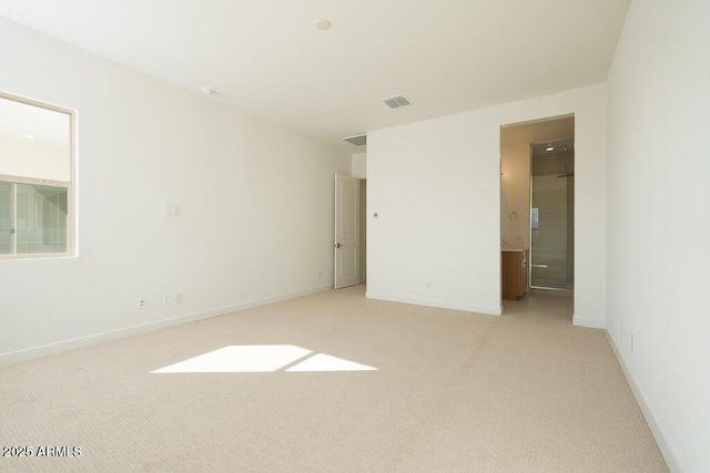 spare room featuring light colored carpet, visible vents, and baseboards