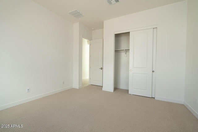 unfurnished bedroom with a closet, baseboards, light colored carpet, and visible vents