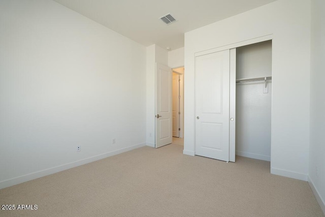 unfurnished bedroom with baseboards, visible vents, a closet, and light carpet