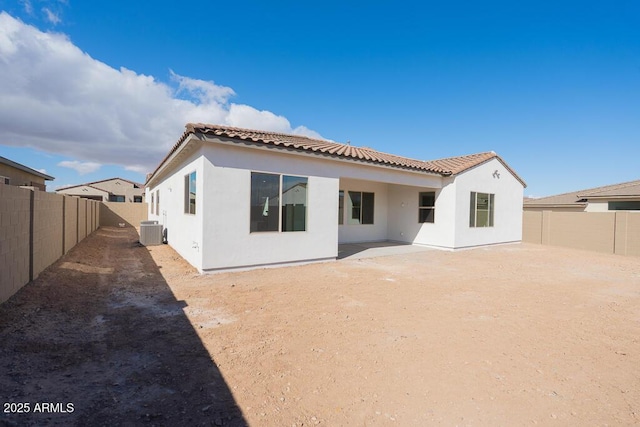 back of property featuring a tiled roof, central air condition unit, a fenced backyard, and stucco siding