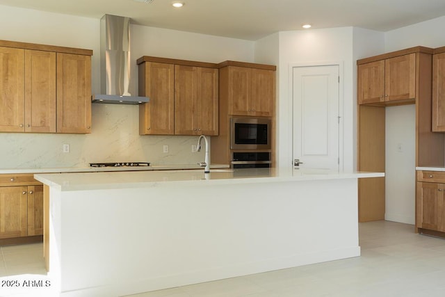 kitchen featuring stainless steel microwave, brown cabinets, oven, and wall chimney range hood